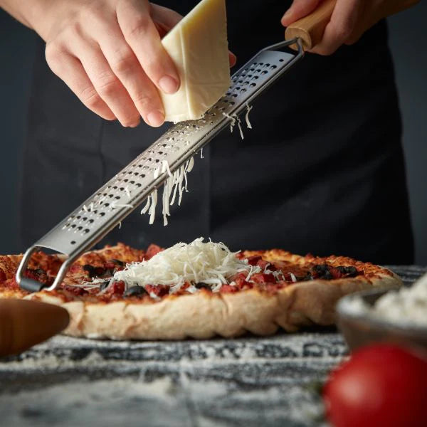 une photo d'une pizza sur la quelle on rape du fromage