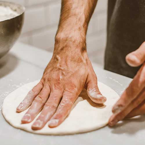 une personne qui prépare une pâte à pizza